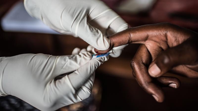 A health worker in Uganda takes a blood sample for an HIV test.