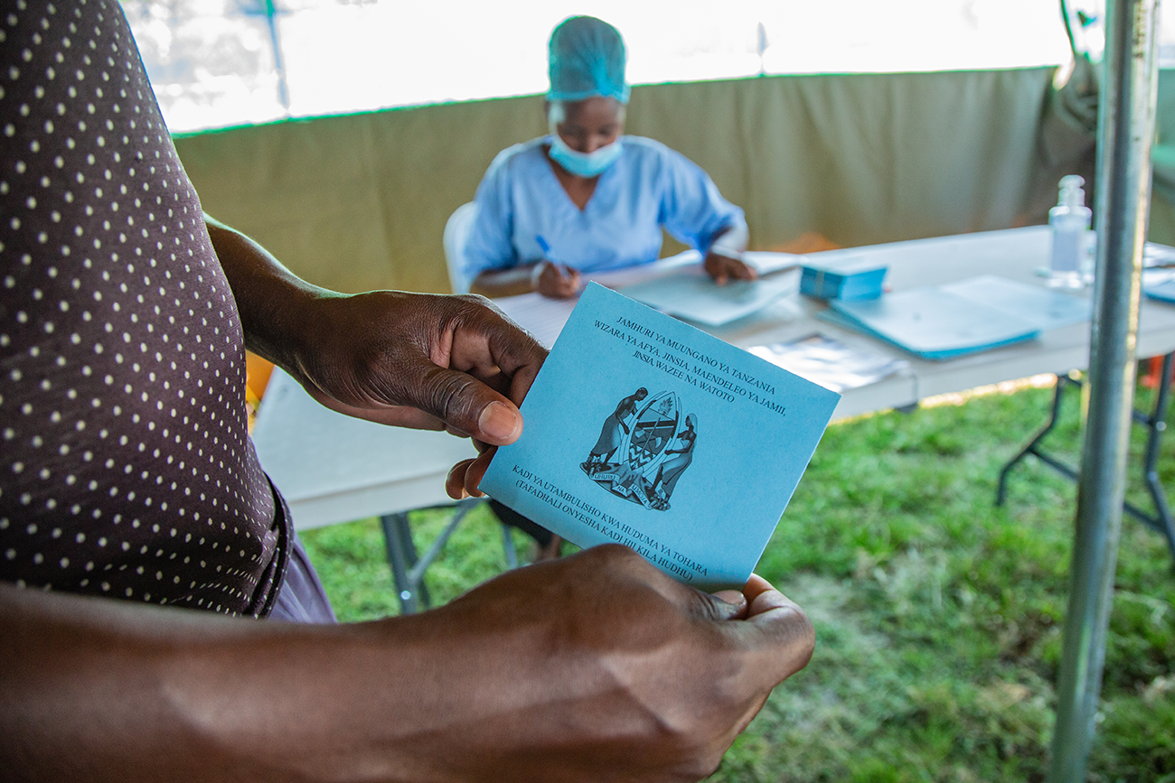A client holds his patient card for before going into the mobile clinic van for HIV testing and the VMMC procedure. Photo by Rashid Hamis Kindamba for IntraHealth International.