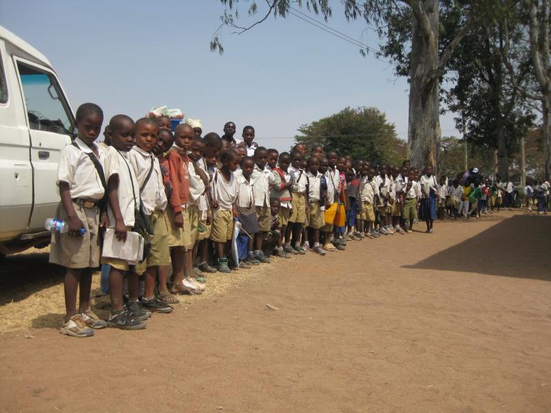 Primary school children wait for the arrival of the Uhuru Torch to celebrate the opening of a male circumcision clinic in Simiyu Region, Tanzania. The Uhuru Torch is carried around the country annually to celebrate Tanzanian Independence (1961) and recognize successful community initiatives. Photo by Abbie Heffelfinger.