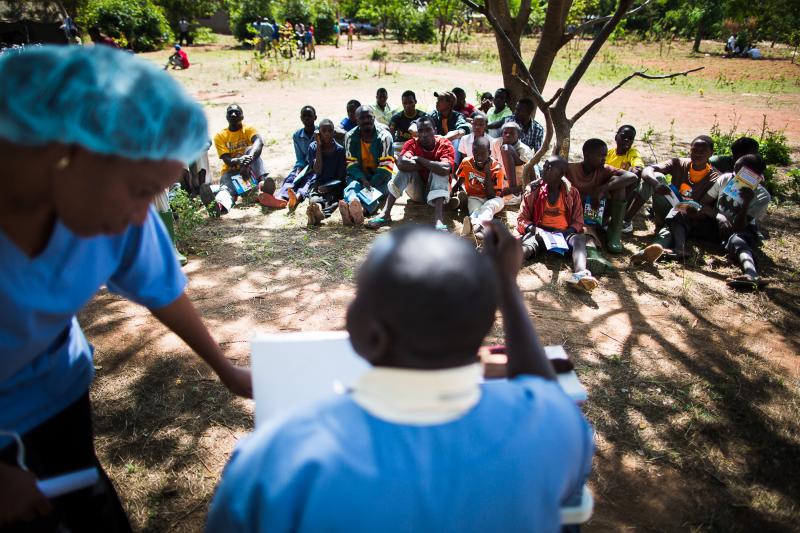 Clients sit in groups of 25 or so to learn about voluntary medical male circumcision and its benefits from HIV counselor William Sita. Photo by Trevor Snapp.